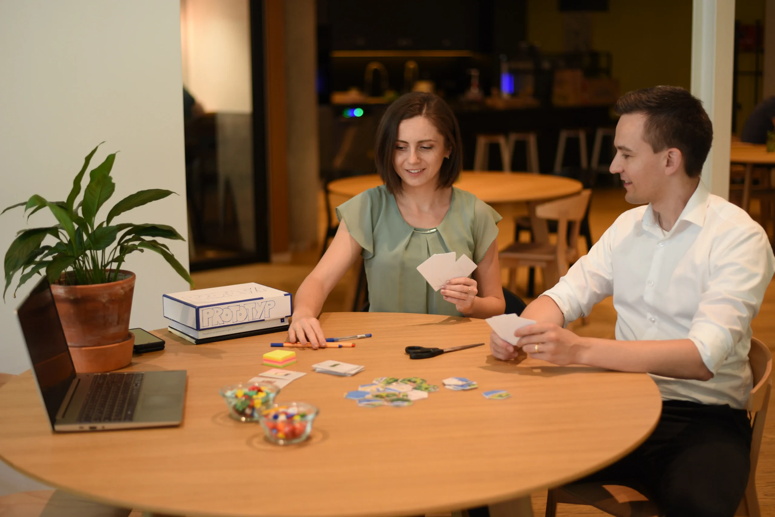 Aleksandra und Christoph entwickeln gemeinsam am Tisch das Brettspiel Look Inside